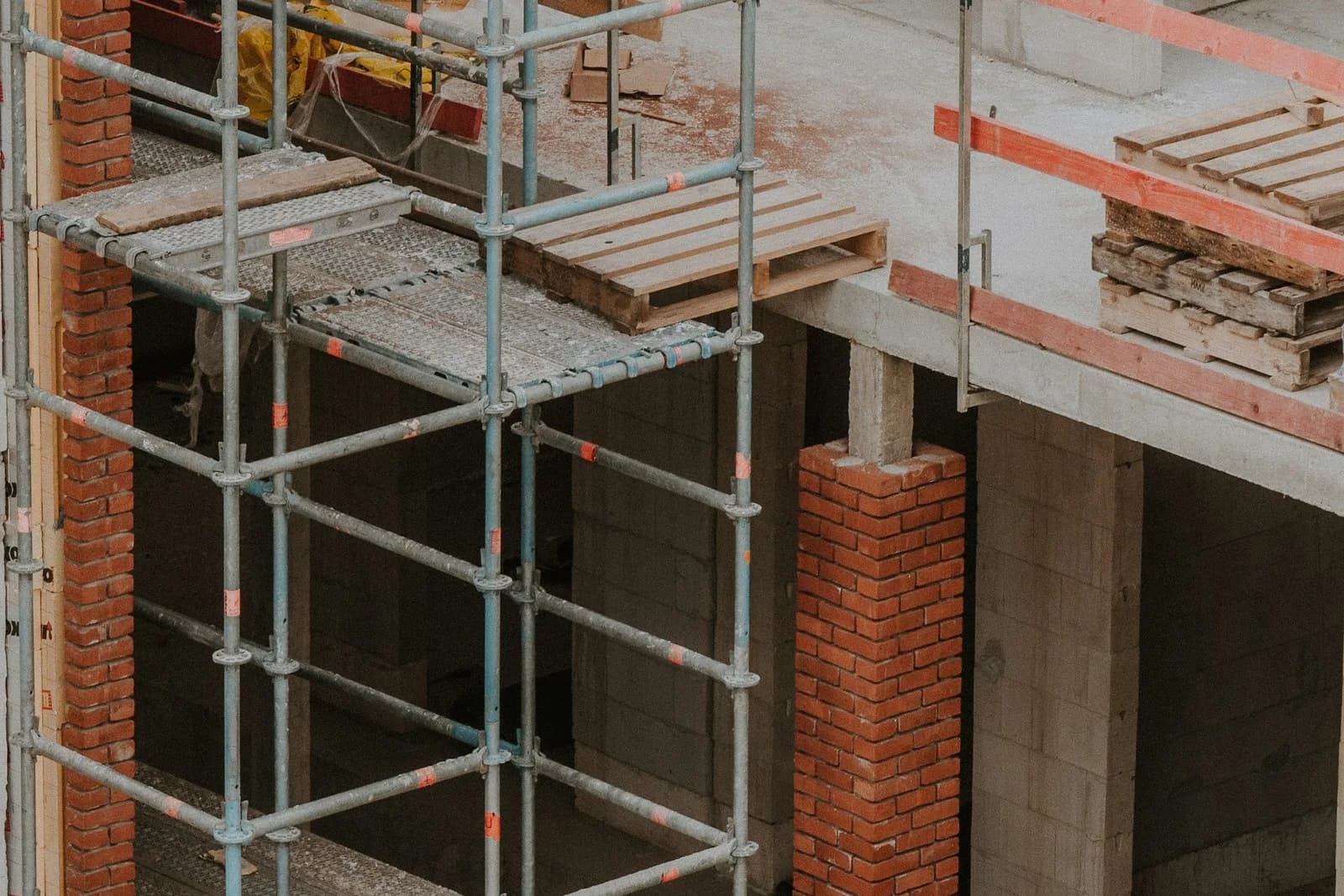 建設中の建物に組まれた単管足場と、赤レンガを積んだ柱