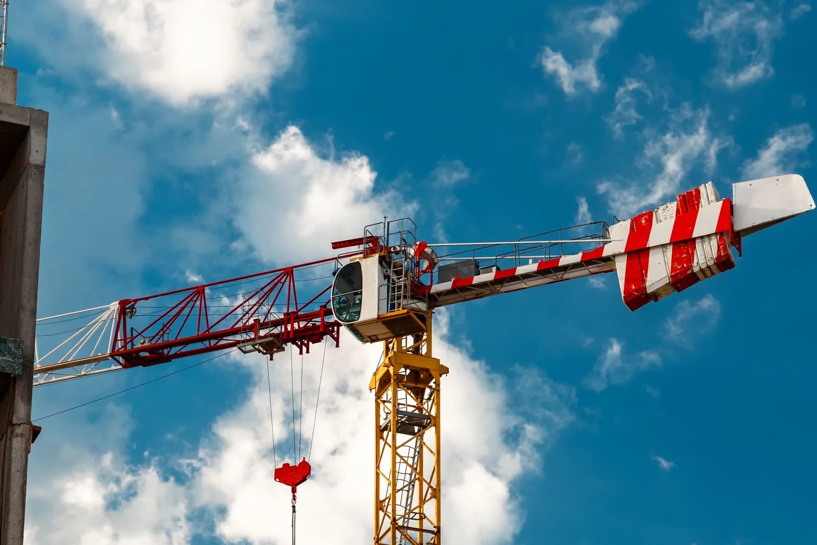 青空にそびえるタワークレーンと建設中の建物